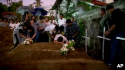 Familiares dejan flores en las tumbas de tres víctimas de una misma familia que murieron en los ataques del Domingo de Pascua en la iglesia de St. Sebastian, en Negombo, Sri Lanka, el 22 de abril de 2019.