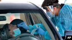 People are tested for COVID-19 in their in vehicles in Phoenix's western neighborhood of Maryvale.