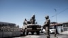 Des soldats de la South African National Defence Force devant un véhicule blindé dans la ville du Cap, le 30 mars 2020, au cours d'une patrouille visant à faire respecter le confinement national de 21 jours. (Photo: AFP)
