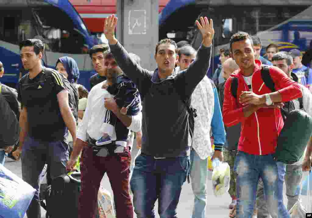 Des réfugiés saluent de la main à leur arrivée à la gare principale de Munich, en Allemagne, 5 septembre 2015.
