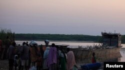 People displaced by the fighting in Bor county, stand by their belongings after arriving in the port of Minkaman, in Awerial county, Lakes state, in South Sudan, Jan. 14, 2014.