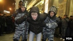 2 polisi di Moskow menangkap seorang nasionalis muda dalam suatu unjuk rasa di Moscow.