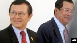 Cambodia's Prime Minister Hun Sen, right, walks with opposition Cambodia Rescue Party Deputy President Kem Sokha, left, during a break at National Assembly in Phnom Penh, Cambodia, Wednesday, Dec. 7, 2016.