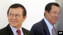Cambodia's Prime Minister Hun Sen, right, walks with opposition Cambodia Rescue Party Deputy President Kem Sokha, left, during a break at National Assembly in Phnom Penh, Cambodia, Wednesday, Dec. 7, 2016. Cambodia's newly pardoned Kem Sokha has returned to parliament with a claim that he and Prime Minister Hun Sen have agreed to help reconcile their contending parties for the sake of benefiting the country. (AP Photo/Heng Sinith)