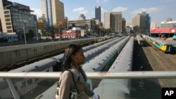 Un résident marche sur le pont Mandela au-dessus de la voie ferrée à Johannesburg, le jeudi 29 juin 2006. (AP Photo/Jerome Delay-file)