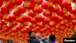 Children play with bubble toy guns under Chinese lunar New Year decorations at a park in Beijing, Jan. 24, 2014.