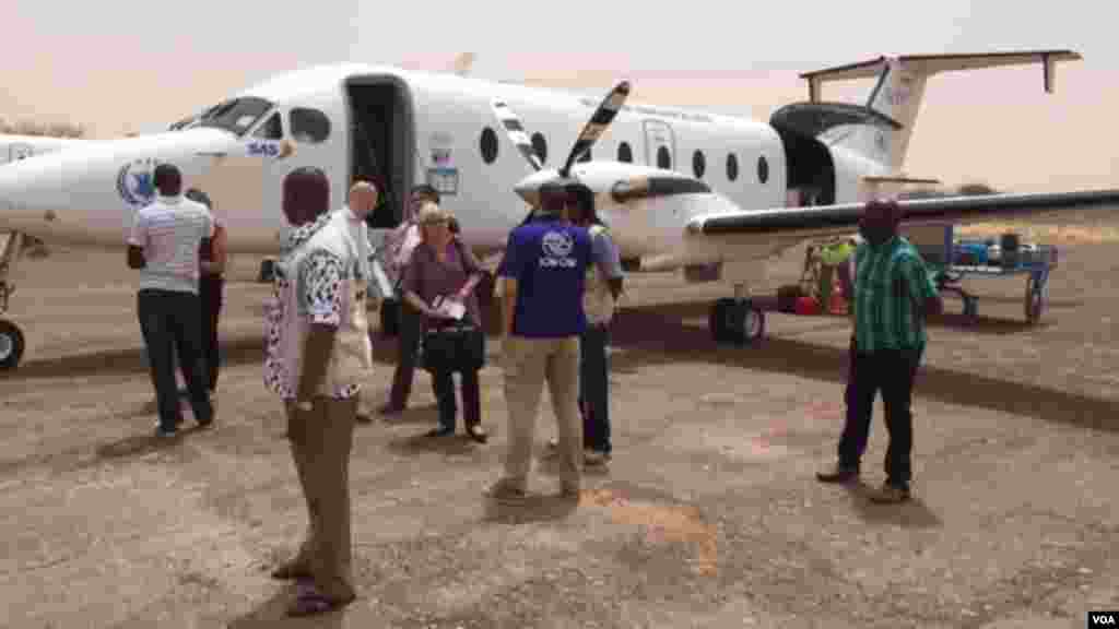 Des journalsites et des travailleurs humanitaires s'apprêtent à s'embarquer dans un avion du Programme mondial pour l'alimnetation à l'aéport de Diffa.
