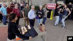 Let Vargas ofrece rollos de canela a los votantes en un puesto de votación en Austin, Texas, donde las primarias demócratas del martes 6 de marzo.