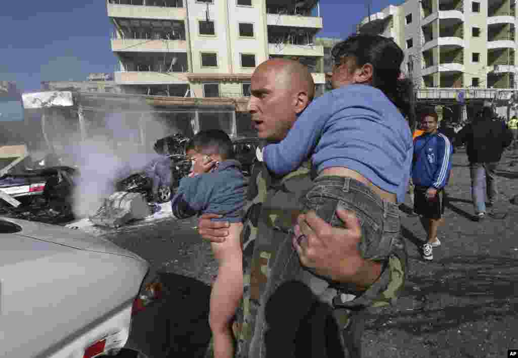 A Lebanese army soldier carries two injured children away from the site of an explosion near the Kuwaiti Embassy and Iran's cultural center, in the suburb of Beir Hassan, Beirut, Lebanon, Feb. 19, 2014.