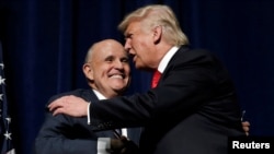 Le président américain Donald Trump (à dr.) embrasse l'ancien maire de la ville de New York, Rudolf Giuliani, lors d'un rassemblement de campagne à Greenville, N.C., le 6 septembre 2016.