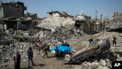 Warga mengangkat jenasah para korban yang jatuh saat terjadinya bentrokan antara pasukan keamanan Irak dan ISIS di wilayah barat Mosul, Irak, 24 Maret 2017. (AP Photo/Felipe Dana)