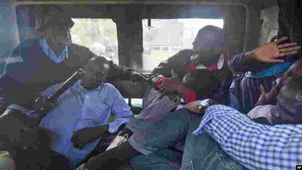 Des manifestants sont battus avec des gourdins au dos à bord d'une camionnette de la police après avoir été arrêté à l'extérieur du bâtiment du Parlement à Nairobi, au Kenya jeudi 18 décembre 2014.