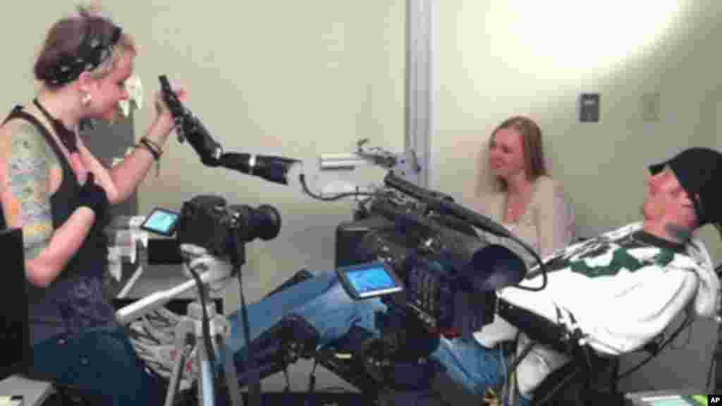 La vidéo fournie par le Centre Médical Center de l'Université de Pittsburgh, prise lundi 19 septembre 2011, montre un sujet tétraplégique,Tim Hemmes, utilisant une prothèse de bras mécanique, avec Katie Schaffer, pendant une des séances d'essais. (AP Photo / UPMC)