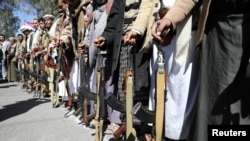 Para pendukung Houthi bersiaga dengan senjata dalam demo di luar Kedutaan Besar AS setelah keputusan AS memasukkan Houthi sebagai organisasi teroris, di Sana'a, Yaman, 18 Januari 2021. 