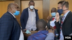 Journalist Hopewell Chin’ono talks to his lawyers Nov. 12, 2020, after Magistrate Marehwanazvo Gofa denied him bail on grounds that he had high propensity to abuse social media again. (Columbus Mavhunga/VOA)