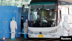 L'équipe de l'OMS chargée d'enquêter sur les origines de la pandémie du COVID-19 monte dans un bus avant de quitter l'aéroport international de Wuhan Tianhe à Wuhan, dans la province de Hubei, en Chine, le 14 janvier 2021.