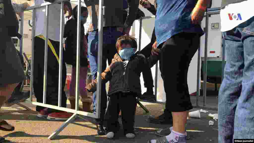 Un niño es visto de la mano de una mujer en un albergue improvisado en Tijuana, donde se encuentran los migrantes esperando entrar a EE.UU. Fotografía: Celia Mendoza- VOA