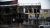 In a photo taken Nov. 18, 2019, and released by the Iranian Students' News Agency, ISNA, people walk past buildings which burned during protests that followed the authorities' decision to raise gasoline prices, in the city of Karaj, west of Tehran.