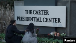 Waombolezaji wakiweka mashada ya maua katika kituo cha Rais Jimmy Carter, baada ya kutangazwa kifo cha chake, Jumapili, Desemba, 29, 2024.