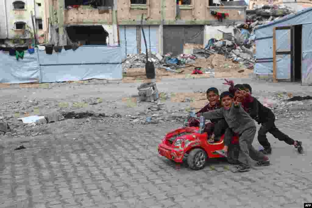 Anak-anak Palestina bermain dengan mobil mainan dekat kamp pengungsi Beit Lahia di Jalur Gaza utara, menjelang waktu berbuka puasa selama bulan suci Ramadan, Minggu 9 Maret 2025. (AFP) 