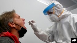 An employee of a new Lufthansa corona quick test center takes a test of a man at the airport in Munich, Germany, Nov. 12, 2020. 