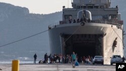 Des migrants attendent devant un navire militaire après leur débarquement dans le port d'Elefsina, près d'Athènes, le samedi 2 novembre 2019. (AP)