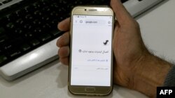 FILE - A man holds a smartphone connected to a Wifi network without internet access, at an office in the Iranian capital Tehran, Nov. 17, 2019.