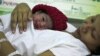 FILE - Danica Camacho is cuddled by her mother as they are wheeled out of the delivery room of the Government's Fabella Hospital moments after she was born October 31, 2011, in the Philippines.
