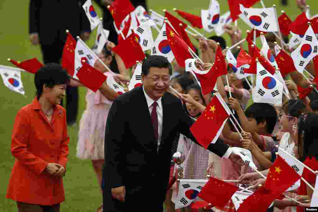 Chinese President Xi Jinping and South Korean President Park Geun-hye greet children waving the two countries' national flags during a welcoming ceremony at the presidential Blue House in Seoul, July 3, 2014.