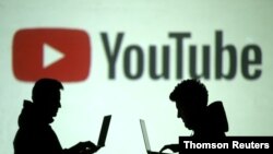 Una ilustración de siluetas de dos usuarios de aparatos móviles se ven frente a un logo de YouTube en esta ilustración de archivo.