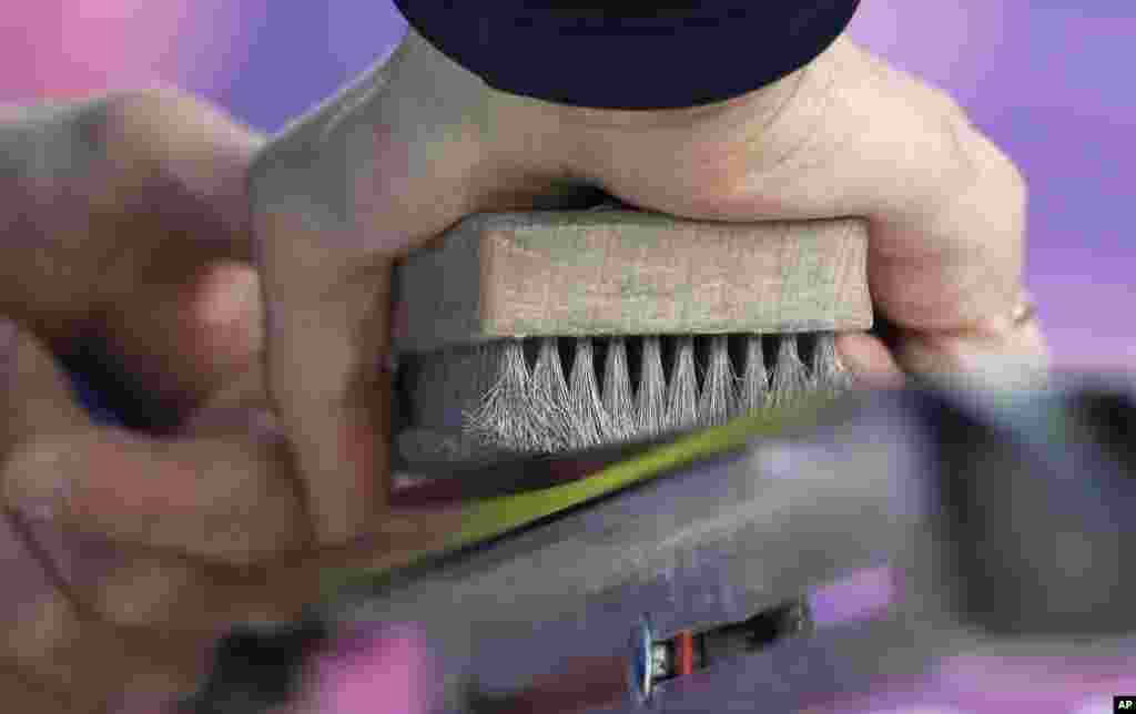 A waxing technician brushes a ski during the cross-country sprint competitions, Krasnaya Polyana, Feb. 11, 2014.