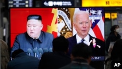 Arhiva - Ljudi gledaj TV program i kombinaciju fotografija severnokorejskog lidera Kim Džon Una i predsednika SAD Džoa Bajdena, na železničkoj stanici u Seulu, Južna Koreja, 26. marta 2021.