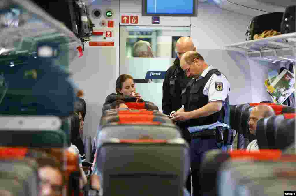 German policemen check passenger's documents on a train in Freilassing, on the border between Austria and Germany. The German government is sticking with its forecast for 800,000 asylum seekers and refugees to arrive in the country this year despite strong inflows in recent weeks, a spokesman for the Interior Ministry said.