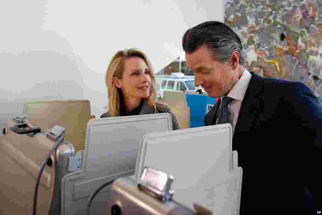 California Gov. Gavin Newsom looks over the ballot of his wife, First Partner Jennifer Siebel Newsom, as they vote on Super Tuesday in Sacramento, Calif., March 3, 2020.