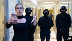 Aktivis oposisi Lyubov Sobol melaporkan secara langsung melalui telepon saat polisi berjaga-jaga selama penggerebekan di kantor Yayasan Anti-Korupsi, di Moskow, Rusia, 26 Desember 2019. (Foto: AP)