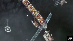 Esta imagen, proporcionada por Maxar, muestra la proa del carguero Dali bajo tramos del puente Francis Scott Key Bridge, mientras equipos de rescate y remolcadoras siguen retirando restos del puente y cientos de contenedores, en Baltimore, el lunes 8 de abril de 2024.