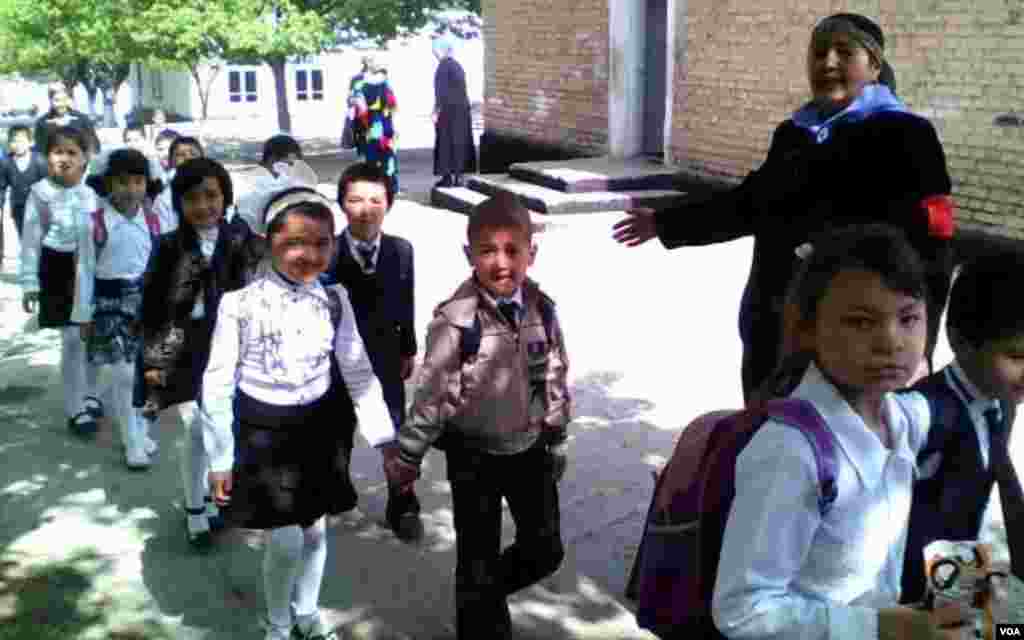Maktab tarbiyachisi qo'yi sinf o'quvchilarini tadbir tufayli ularga alohida tayyorlangan bayram dasturxoniga olib bormoqda