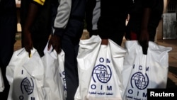 FILE - Gambian migrants repatriated from Libya stand in line with plastic bag from the International Organization for Migration (IOM) as they wait to be registered at the airport in Banjul, Gambia, April 4, 2017.
