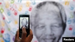 Une banderole à l'effigie de l'ancien président sud-africain Nelson Mandela, est prise en photo à Pretoria, le 18 juillet 2013.