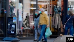 Para pejalan kaki mengenakan masker wajah berjalan melintas sebuah toko di tengah wabah virus corona, di Leipzig, Jerman Timur, 20 April 2020. (Foto: AFP)