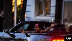 En esta foto tomada el 26 de junio de 2020, una mujer grita mientras conduce por Miami Beach, Florida. El 27 de junio de 2020 el estado alcanzó un nuevo récord diario de casos de coronavirus de casi 10,000.