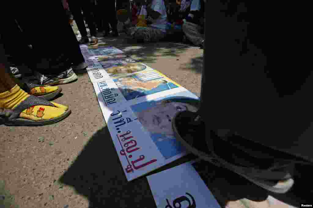 Anti-government protesters step on a poster of ousted Thai prime minister Yingluck Shinawatra outside the National Broadcast Services of Thailand (NBT) television station, in Bangkok, May 9, 2014.