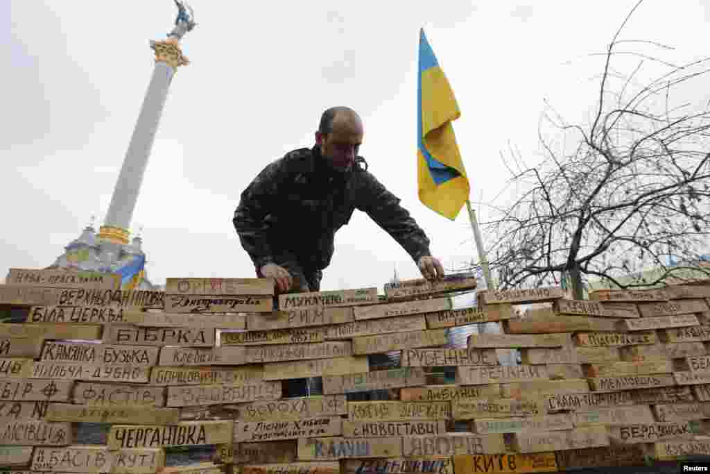 A man stacks wooden bars showing names of Ukrainian cities and settlements that are hometowns of demonstrators, during a rally in Independence Square in Kyiv, Dec. 16, 2013.