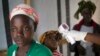 FILE - A health worker checks the temperature of a girl at the entrance to a Red Cross facility in the town of Koidu, Sierra Leone.