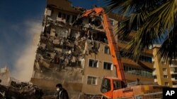 Un trabajador pasa frente a un edificio dañado por el sismo del 30 de octubre que obreros están demoliendo. Esmirna, Turquía, 4 de noviembre de 2020.