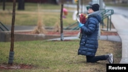 Femme priant devant le centre hospitalier de soins de longue durée Herron, où près de 50 personnes sont mortes du coronavirus, Dorval, Québec, Canada, 13 avril 2020. Une enquête publique a été ordonnée en juin. (REUTERS/ Christinne Muschi)