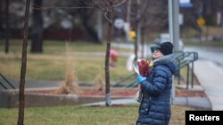 Une femme prie en laissant des fleurs à l'extérieur de la résidence Herron, un établissement de soins pou personnes âgées, après plusieurs pendant l'épidémie de COVID-19, dans la banlieue de Dorval à Montréal, Québec, Canada, le 13 avril 2020. (Photo: REUTERS / Christinne Muschi)