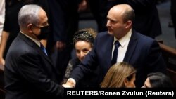 Pemimpin partai oposisi Benjamin Netanyahu menjabat tangan PM baru Israel Naftali Bennett di Yerusalem, Minggu (13/6). 