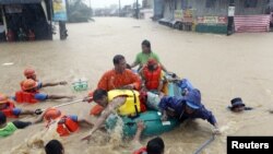 Regu penolong mendorong perahu karet dan mengevakuasi warga dari rumah mereka yang terkena banjir di wilayah Marikina, Manila, Filipina (7/8).
