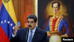 Presiden Venezuela Nicolas Maduro menunjukkan salinan Konstitusi Nasional saat dia berbicara pada konferensi pers di Istana Miraflores di Caracas, Venezuela, 9 Januari 2019. 